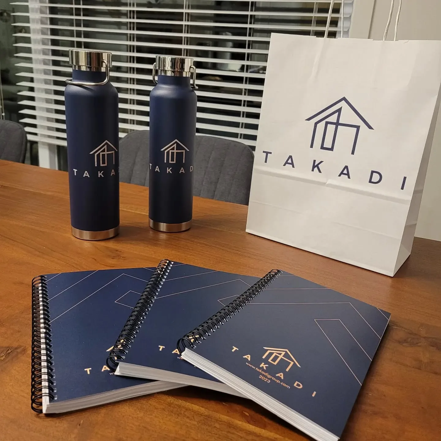 Kit d'accueil Takadi : gourdes, cahiers et sac à l'effigie de Takadi sur une table en bois
